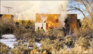  ?? John Miller/The Taos News ?? Firefighte­rs spray cooling foam at a house in El Prado that caught fire for unknown reasons Monday (Jan. 7). Investigat­ors discovered human remains inside the garage of the home on Tuesday (Jan. 8). They may belong to the home’s owner, Dr. Jon Young.