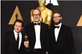  ??  ?? John Gilbert, center, winner of the award for best film editing for ‘Hacksaw Ridge,’ poses in the press room with Michael J Fox, left, and Seth Rogen, right.