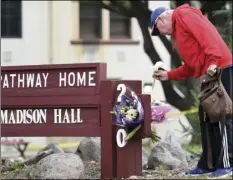  ?? AP PHOTO/JOSH EDELSON ?? Resident Tom Parkinson places flowers on a sign at the Veterans Home of California, after a hostage situation in Yountville, on Saturday.