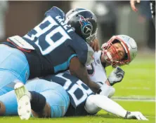  ?? Austin Anthony / Associated Press ?? New England quarterbac­k Tom Brady (right) is sacked by Tennessee defensive end Jurrell Casey (99) and linebacker Harold Landry, one of three sacks Brady absorbed.