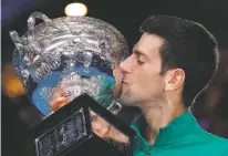  ?? LEE JIN-MAN/ASSOCIATED PRESS ?? Serbia’s Novak Djokovic kisses the Norman Brookes Challenge Cup after defeating Austria’s Dominic Thiem in the men’s singles final of the Australian Open on Sunday in Melbourne, Australia.