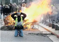  ?? PHOTO: REUTERS ?? Burning issues . . . A protester wearing a yellow vest poses in front of a burning barricade during a demonstrat­ion of the yellow vests movement in Nantes, France, on Saturday.