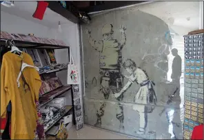  ?? (AP/Nasser Nasser)* ?? A mural by Banksy is covered with protective glass Aug. 4 inside a gift shop in Bethlehem.