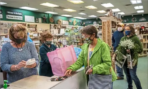  ?? Michael M. Santiago/Post-Gazette ?? Michelle Stiglitz, of Franklin, left, works the register Friday at Nells at Cranberry Mall in Cranberry, Venango County, while owner Jane Harmon, center, packs the bag of shopper Maxine Milford, of Parker.