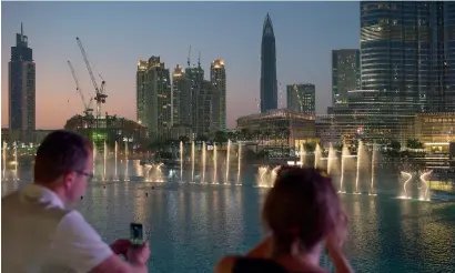 ?? — Bloomberg ?? Tourists click photos of the Dubai Fountain in Downtown Dubai. Even with a recent softening, Dubai’s hotels boasted one of the world’s highest occupancy rates at 84.9 per cent in November 2015.