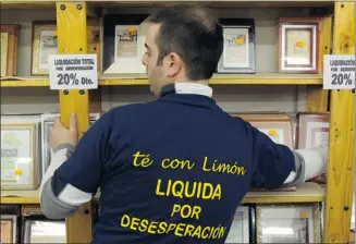  ?? Sergio Perez, Reuters ?? A Te Con Limon employee wears a T-shirt printed with the words “Tea with Lemon: Sales due to desperatio­n” in Madrid on Monday. The shop, like thousands of others, has been forced to close.