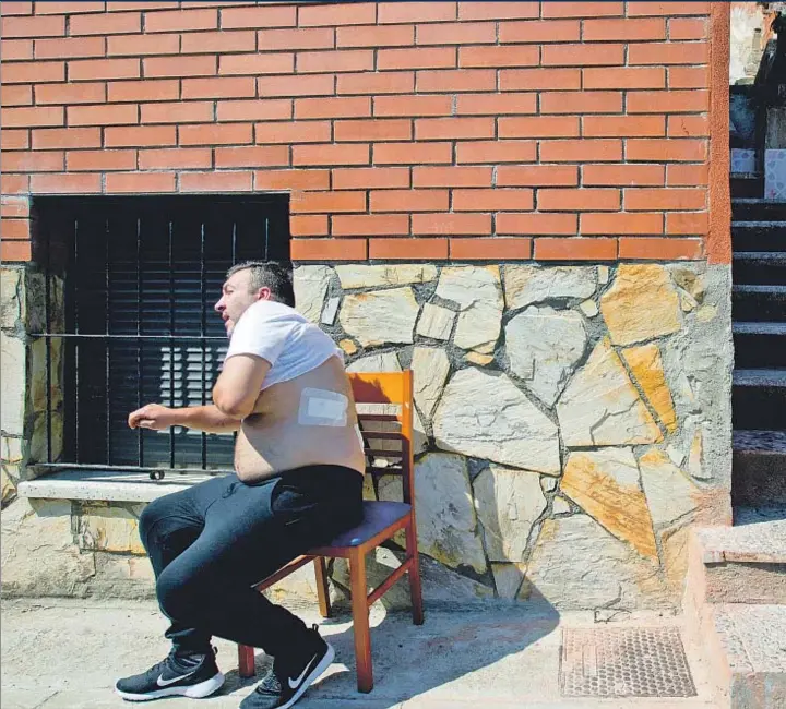  ??  ?? Jaime Bares muestra frente a su casa los efectos del disparo que sufrió por proteger a su familia y a Isabel, de pie junto a él con una de sus hijas en brazos
