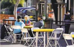  ?? ERIC RISBERG AP ?? People sit at tables on a street closed off for outdoor dining Friday in Sausalito. Bay Area health officers issued a new stay-at-home order Friday.