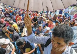  ?? Orlando Sierra AFP/Getty Images ?? CENTRAL AMERICANS who are part of a migrant caravan heading to the United States wait to cross into Mexico from Guatemala on Monday.