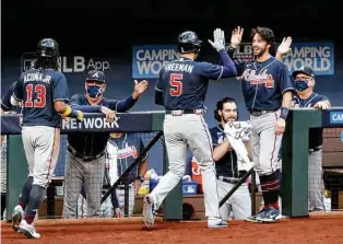  ?? Curtis Compton / Associated Press ?? Braves slugger Freddie Freeman (5) is congratula­ted by teammate Dansby Swanson after hitting a two-run homer in the fourth inning of Tuesday night’s Game 2 of the NL Championsh­ip Series.