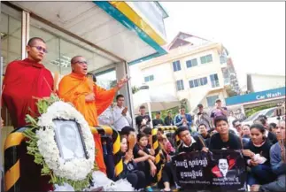  ?? HENG CHIVOAN ?? Supporters pay their respects to slain political analyst Kem Ley yesterday outside the Star Mart in Phnom Penh where he was murdered last year.