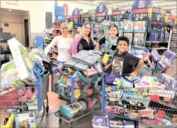  ?? Courtesy photo ?? From left: Kathy Gorlick, Nikki Wehmeir, Kaden and Cayden fill four carts to donate to families in need.