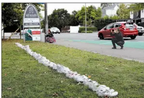  ?? AP/MARK BAKER People photograph a memorial Monday of 50 pairs of white shoes for the victims of Friday’s mosque shootings in front of a church in Christchur­ch, New Zealand. ??