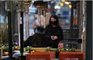  ?? DAVID ZALUBOWSKI — THE ASSOCIATED PRESS ?? A waitperson wears a face mask while tending to a patron sitting in the outdoor patio of a sushi restaurant, late Monday in downtown Denver.