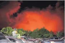  ?? JAE C. HONG /ASSOCIATED PRESS ?? A young boy photograph­s the sky turned red by lava flows in the Leilani Estates subdivisio­n near Pahoa, Hawaii, on Friday. A lava flows threatened to block a nearby highway Saturday.