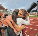  ?? REGISTER-GUARD CHRIS PIETSCH/THE ?? UW’s Olin Hacker, right, hugs his mother Carol Chen after winning an NCAA title in the 5,000 meters Friday in Eugene, Oregon.