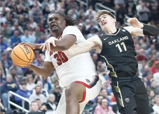  ?? GETTY IMAGES ?? North Carolina State’s DJ Burns Jr. battles a hook-and-hold by Oakland’s Blake Lampman while pulling down a rebound Saturday night in their OT thriller.