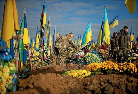  ?? AP ?? A Ukrainian serviceman places flowers on the grave of a recently killed comrade in Kharkiv during Ukraine Defenders Day yesterday. Moscow-installed authoritie­s in Ukraine’s occupied southern region of Kherson have urged local residents to evacuate to Russia, as Kyiv’s forces push their counteroff­ensive deeper into the region.