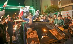  ?? AP ?? A girl holds up posters of Ebrahim Raisi from a car in a campaign rally in Tehran. —