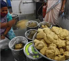 ??  ?? a staff prepares and divides papadum dough into protions.