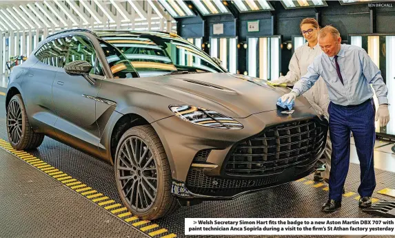  ?? BEN BIRCHALL ?? Welsh Secretary Simon Hart fits the badge to a new Aston Martin DBX 707 with paint technician Anca Sopirla during a visit to the firm’s St Athan factory yesterday