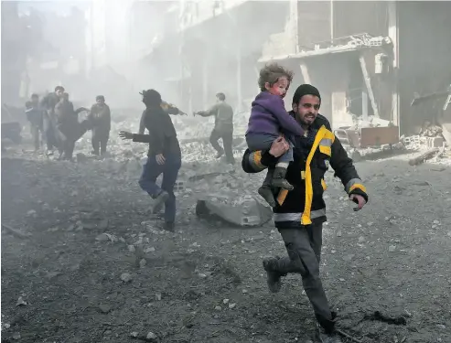  ?? ABDULMONAM EASSA / AFP / GETTY IMAGES ?? A man rescues an infant after a bombing raid on the outskirts of the Syrian capital Damascus on Sunday. At least 71 people were killed and more than 300 were injured in 24 hours of intense bombing in eastern Ghouta, observers said.