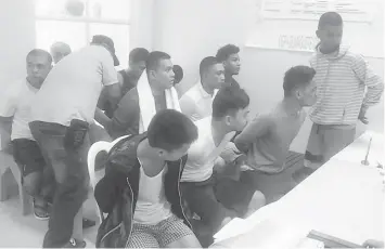  ?? JUANCHO R. GALLARDE ?? The 12 arrested suspects in counterfei­t credit cards are handcuffed during the inquest proceeding­s of their cases at the NBI-Dumaguete office.