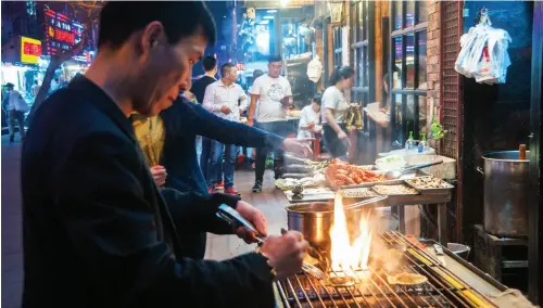  ??  ?? Opening image: Crayfish (yabbies) along with seafood are the main draw on Shouning Road in Shanghai.
From right to below: Sheng jian bao in the heavy iron cooking skillet waiting for eaters at Da Hu Chun restaurant in Shanghai; A chef cooks scallops...