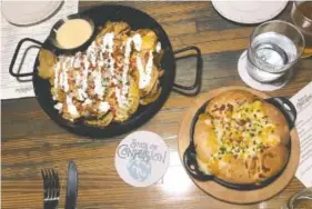  ??  ?? Two starters, Potato Chip Nachos and Savory Monkey Bread, are served in cast-iron skillets. The nachos feature a light dusting of toppings that could be more evenly distribute­d, complement­ed with an excellent cheese dip.