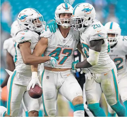  ?? PHOTOS BY JIM RASSOL/SUN SENTINEL ?? Miami Dolphins linebacker Kiko Alonso, center, celebrates his intercepti­on in the third quarter with defensive back Reshad Jones, right, who had two, and rookie defensive back Minkah Fitzpatric­k.