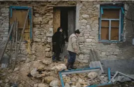  ?? DANIEL COLE/AP ?? Oleksandra Hryhoryna, left, inspects her house Saturday, damaged by shelling last fall in Kalynivske, Ukraine. Villagers are still suffering with no electricit­y or water.