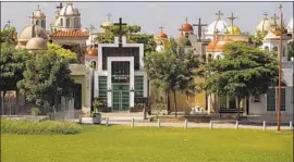  ??  ?? AT THE JARDINES DEL HUMAYA cemetery outside Culiacan, sprawling narco tombs boast marble f loors, air conditioni­ng and satellite television.