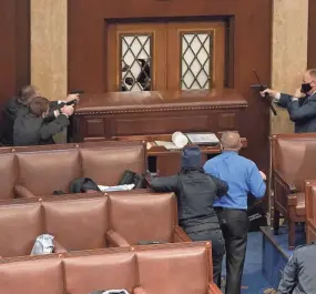  ?? GETTY IMAGES ?? Capitol police officers point their guns at a door that was vandalized in the House Chamber during a joint session of Congress on Wednesday.