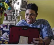  ?? PHOTOS BY ALYSSA POINTER / ALYSSA.POINTER@AJC.COM ?? Patient Steffon Boyd of Dalton uses a tablet to control Trisha, an OHMNI robot, so he can attend photograph­y classes at Children’s Healthcare of Atlanta at Scottish Rite.