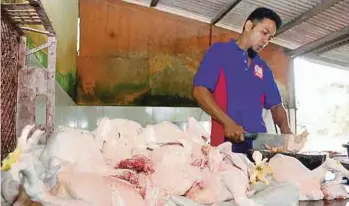  ??  ?? PEMBANTU Shamsul Bokhari, Affendi Bokhari memotong ayam yang dipesan pelanggan di Kampung Solok Duku, Masjid Tanah.