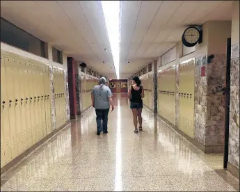  ?? JERRY DAVICH/POST-TRIBUNE ?? Stacy Siegmund and Karen Walker stroll down an empty hallway inside Andrean High School in Merrillvil­le on Sept. 16.