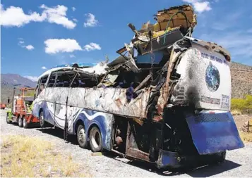  ?? NEMESIO MÉNDEZ JIMÉNEZ AP ?? The wreckage of a bus sits attached to a tow truck the side of the road near Villa de Tepelmeme in Oaxaca, Mexico, on Friday. At least 16 migrants from Venezuela and Haiti died in the crash, authoritie­s said.