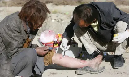  ??  ?? KABUL, Afghanista­n: In this photo, an Afghan first aid nurse with Bridge Hope Health Organizati­on (BHHO) right, dresses the wounds of a drug addict in Kabul, Afghanista­n. —AP photos