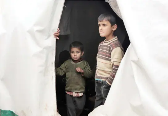  ??  ?? Syrian children, evacuated from Aleppo, stand inside a tent at a refugee camp near Idlib. (AP)