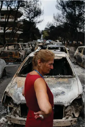  ??  ?? A woman surveys damage following a wildfire at the village of Mati, near Athens. Photo: Reuters