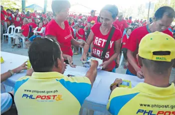  ??  ?? PEOPLE in far-flung areas of the country receiving cash grants and payout services from PHLPost employees who were tapped to serve as relay for internatio­nal humanitari­an groups.