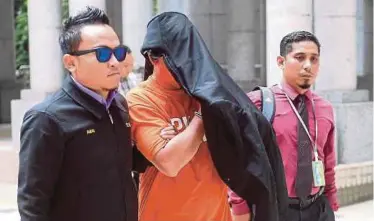  ?? BERNAMA PIC ?? The senior assistant commission­er of police, who holds a ‘Datuk’ title, being escorted out of the magistrate’s court in Putrajaya yesterday.
