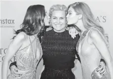 ?? PATRICK KOVARIK, AFP/GETTY IMAGES ?? Bella, left, and Gigi Hadid kiss their mom. Hadid’s son, Anwar, also is a model.