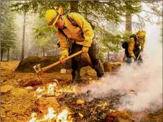  ??  ?? Northern Sonoma County Fire District firefighte­rs Erik Padilla, left, and Joe Young extinguish hot spots while working to protect Lake Almanor West houses from the Dixie Fire on Thursday in Plumas County, Calif.