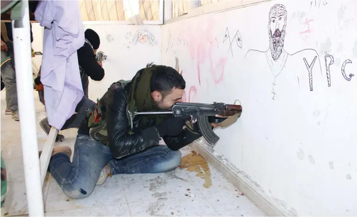  ?? (Courtesy) ?? YPG FIGHTERS on a rooftop in Sere Kaniye/Ras al Ain in 2013.