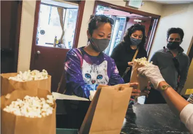  ?? Photos by Brontë Wittpenn / The Chronicle ?? In her cat sweatshirt, Cathy Ye grabs popcorn before sitting down at the Roxie Theater’s CatVideoFe­st.