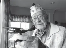  ?? AP/ERIC RISBERG ?? Retired U.S. Navy Cmdr. Don Long holds up a replica Friday of the military seaplane he was standing watch on when Japanese warplanes attacked Hawaii 77 years ago at his home in Napa, California.