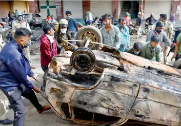  ?? — SATISH B. ?? Locals help move burnt vehicles at Devar Jeevana Halli in Bengaluru on Wednesday.