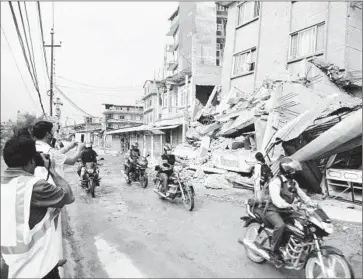  ?? Molly Hennessy-Fiske
Los Angeles Times ?? BINOD TIWARI photograph­s damaged structures in his native Nepal. The magnitude 7.8 earthquake in April has given the Cal State Fullerton engineer a chance to see which buildings and infrastruc­ture held up.