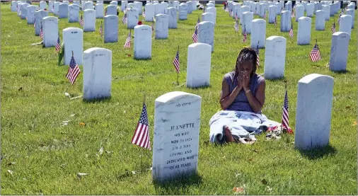  ?? ASSOCIATED PRESS ?? Jennifer Davis of Stafford, Va., wipes her face from the heat as she spends time at the grave of her ex-husband, Staff Sgt. Allen Davis, during a visit to Arlington National Cemetery in Arlington, Va., on Memorial Day.